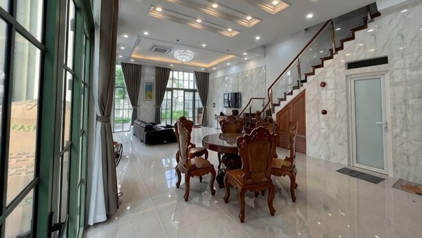 A spacious dining area with a round table and chairs, a staircase, and a large window. - Sunrise Villa (Phu Quoc Island)