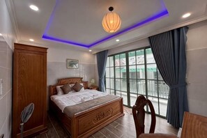 Un dormitorio con cama, armario de madera, mesita de noche y vistas al exterior a través de un ventanal grande.