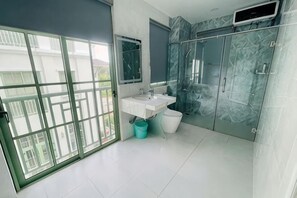 Un baño con un amplio ventanal corredero, un lavamanos, un espejo y una zona de ducha.