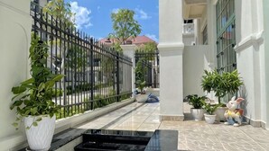 A narrow pathway with potted plants, a black water feature, and a white wall. - Sunrise Villa (Phu Quoc Island)