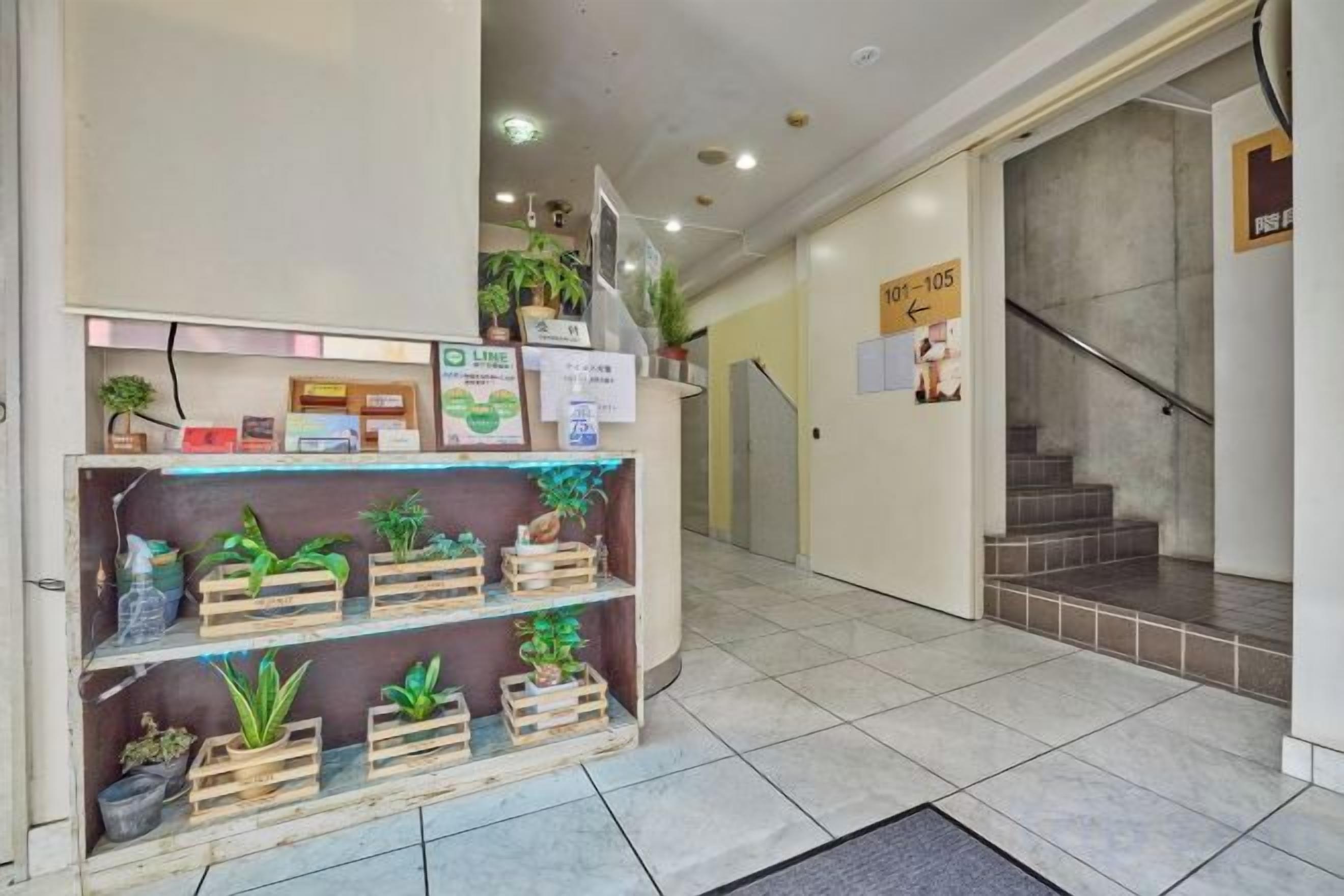 A reception area with a plant display, a staircase, and a sign with a phone number.