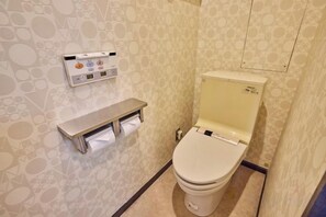 A bathroom with a toilet, a paper towel dispenser, and a toilet paper roll. - HOTEL GRAND FORT (Tokyo)