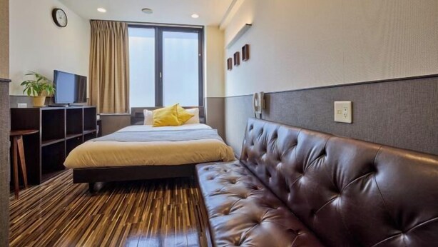 A hotel room with a bed, a TV, a desk, a plant, and a window. - HOTEL GRAND FORT (Tokyo)