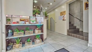 A reception area with a wooden plant display, a staircase, and a sign indicating room numbers 101-105. - HOTEL GRAND FORT (Tokyo)