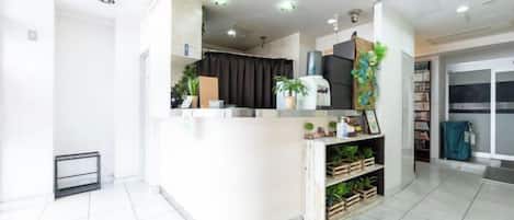 A reception area with a counter, plants, and a view of the outside.
