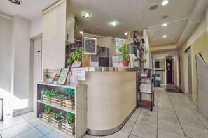 A reception area with a curved counter, potted plants, and a tiled floor. - HOTEL GRAND FORT (Tokyo)