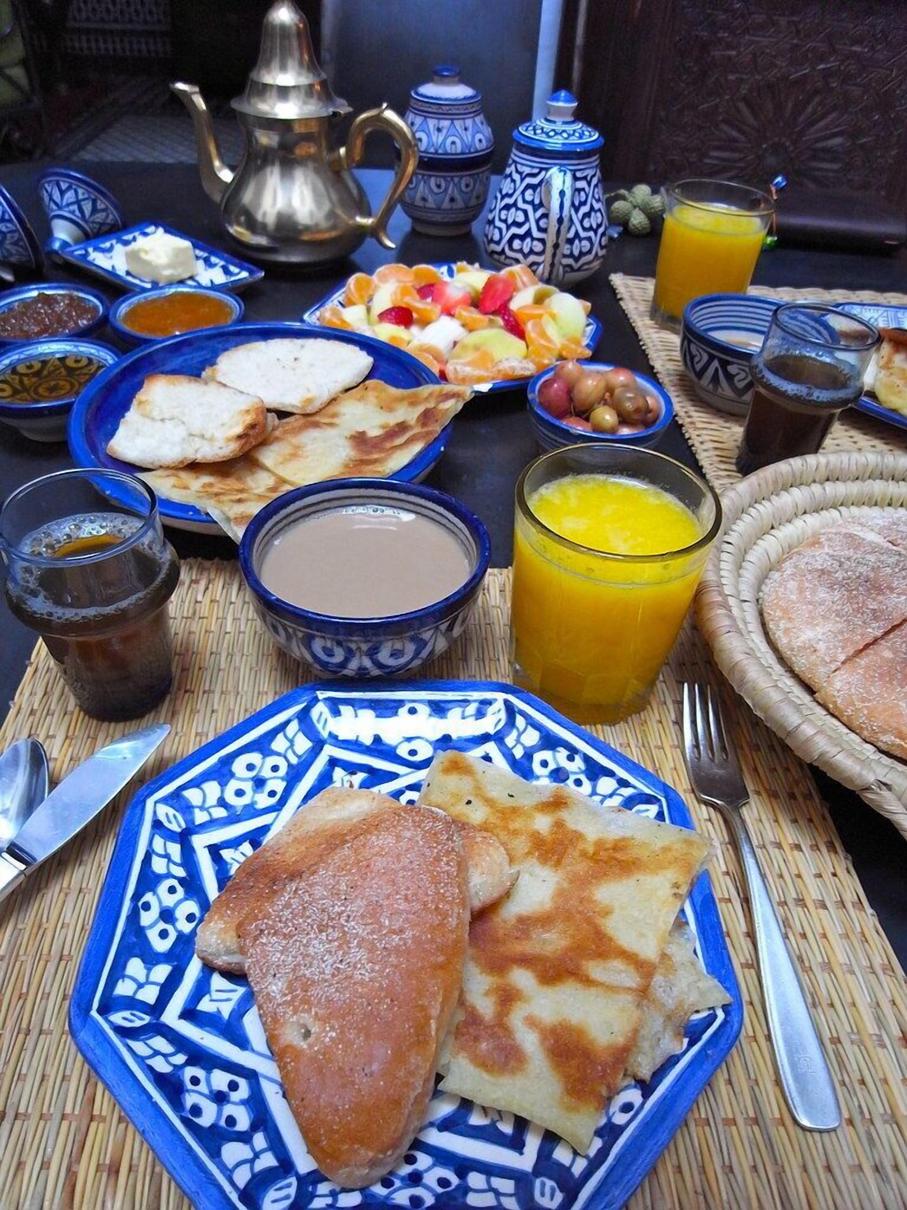 A breakfast table with various dishes, including bread, fruit, and beverages.