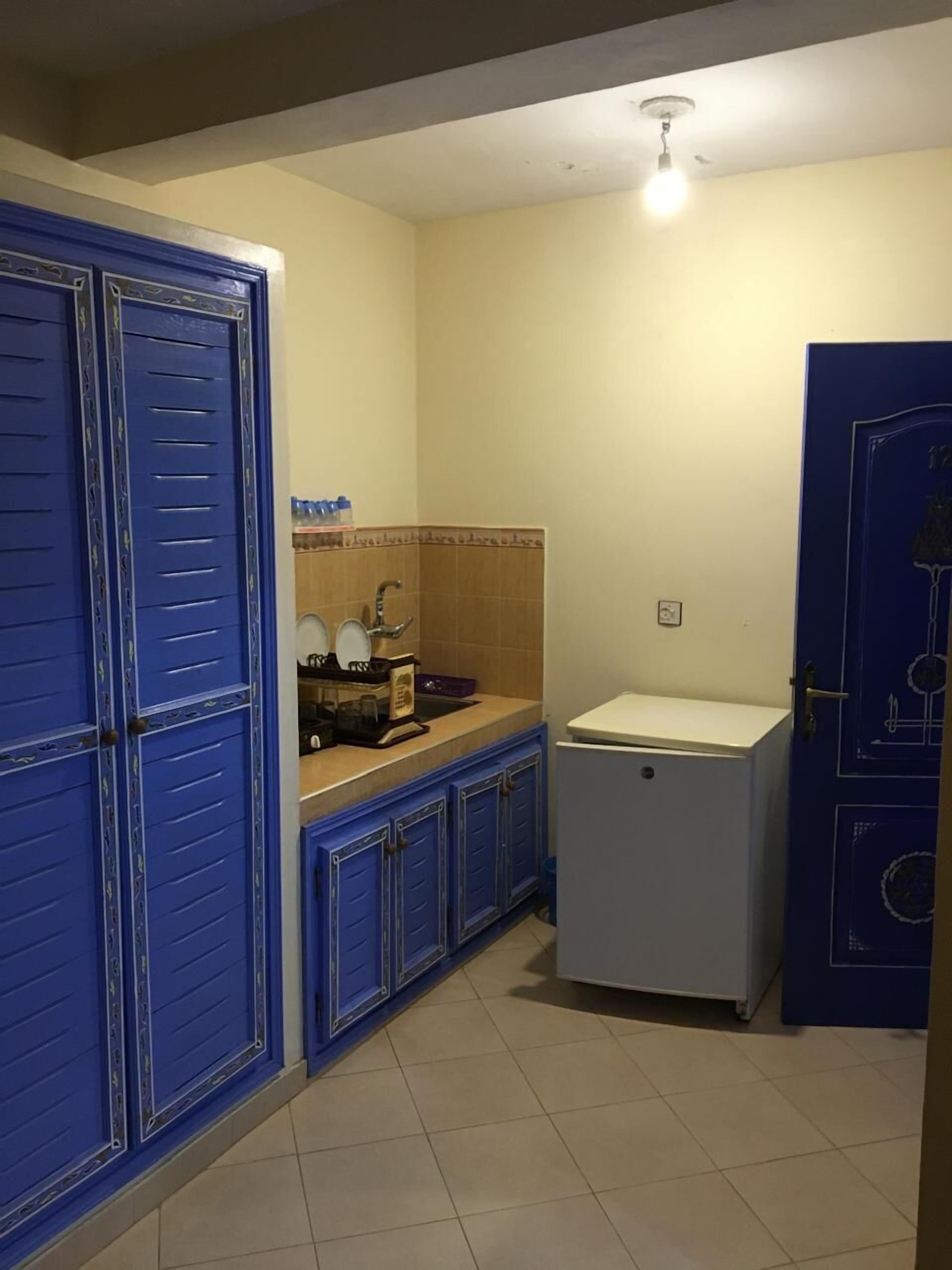 A compact kitchen with blue cabinets, a white refrigerator, and a sink.