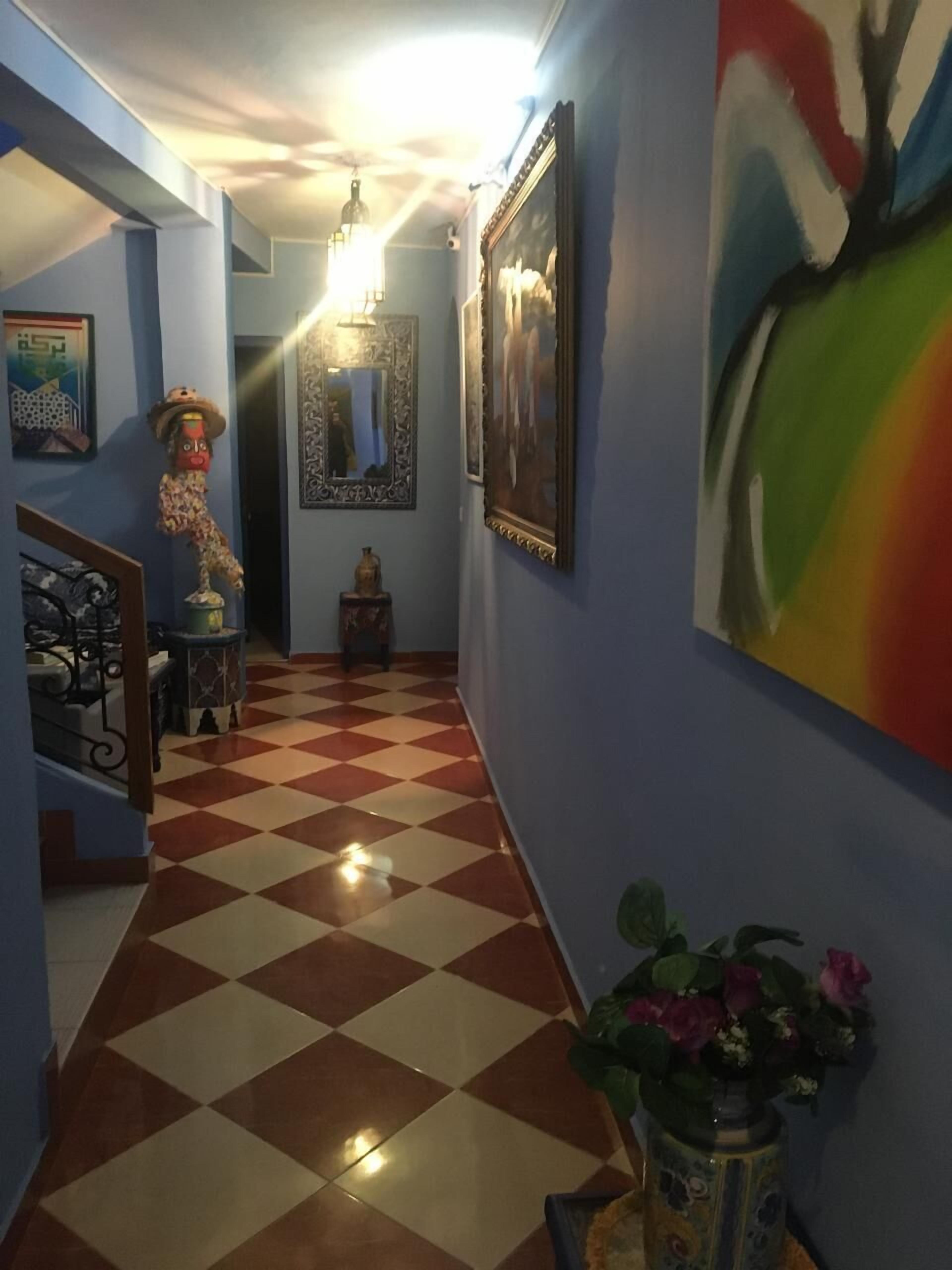A hallway with a checkered floor, blue walls, and a staircase.