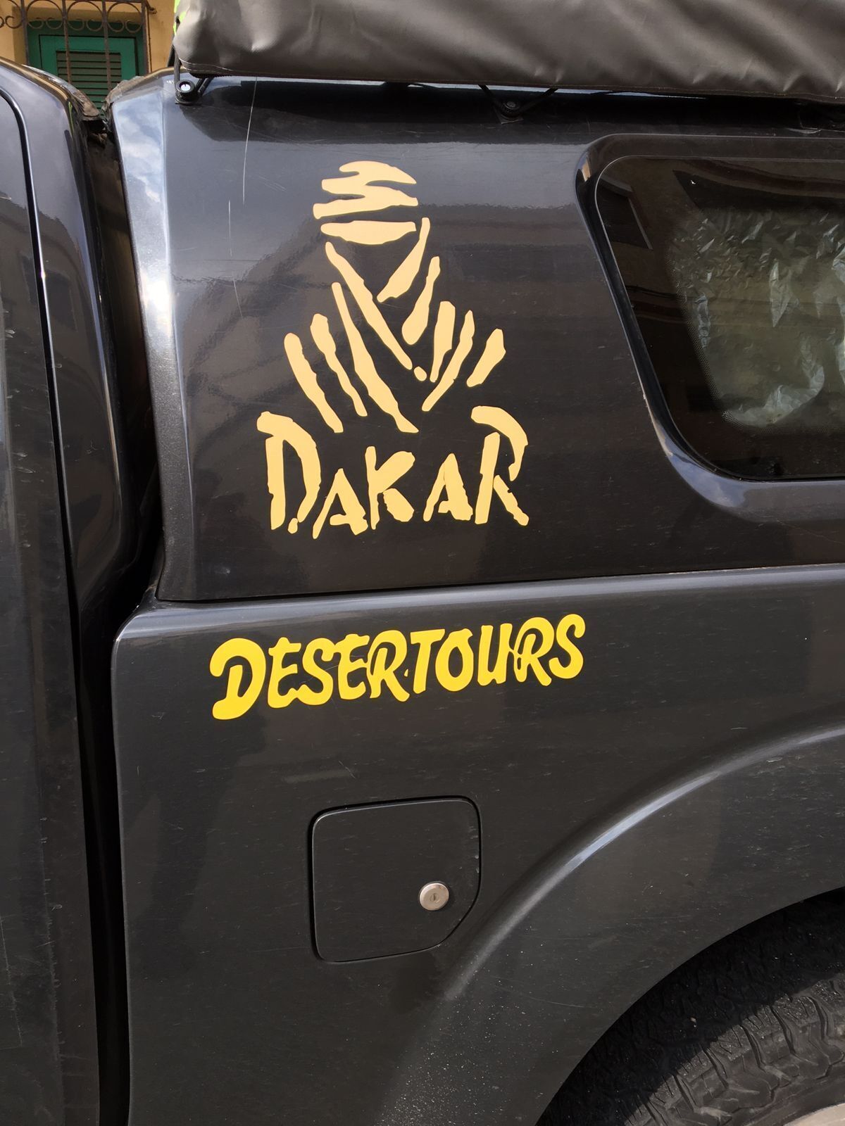 Un vehículo con la leyenda 'DAKAR' y 'DESERTOURS' en su lateral.