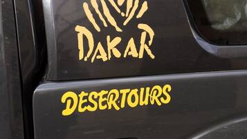Un vehículo con la leyenda 'DAKAR' y 'DESERTOURS' en su lateral.