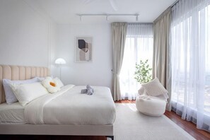 A modern hotel room with a large bed, a bedside table, a chair, and a window with curtains. - Paraiso Residence Bukit Jalil by Feel Home (Kuala Lumpur)