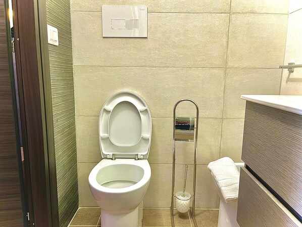 Un baño con inodoro, secamanos y toallero.