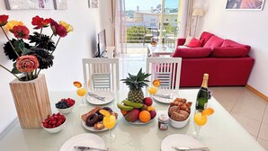 Un'area pranzo con un tavolo apparecchiato per la colazione, con frutta, pasticcini e bevande.