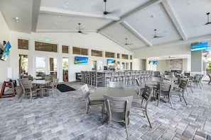 A spacious indoor dining area with multiple tables and chairs, a bar area, and large windows.