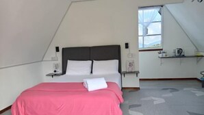 Un dormitorio con cama, mesita de noche, ventana y estante con objetos.