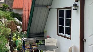 A small patio with a table and chairs, a potted plant, and a metal structure.