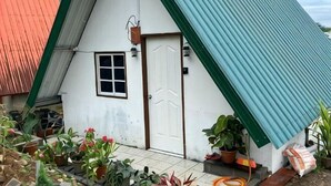 Un pequeño edificio blanco con techo verde y una sola puerta.