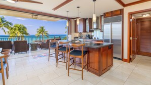Una cucina con vista sull'oceano, un angolo bar con sgabelli e una zona pranzo con sedie.