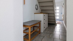 A narrow hallway with a staircase, a wooden bench, a small table, and a cabinet. - Boardinghouse - temporary living (Frohburg)