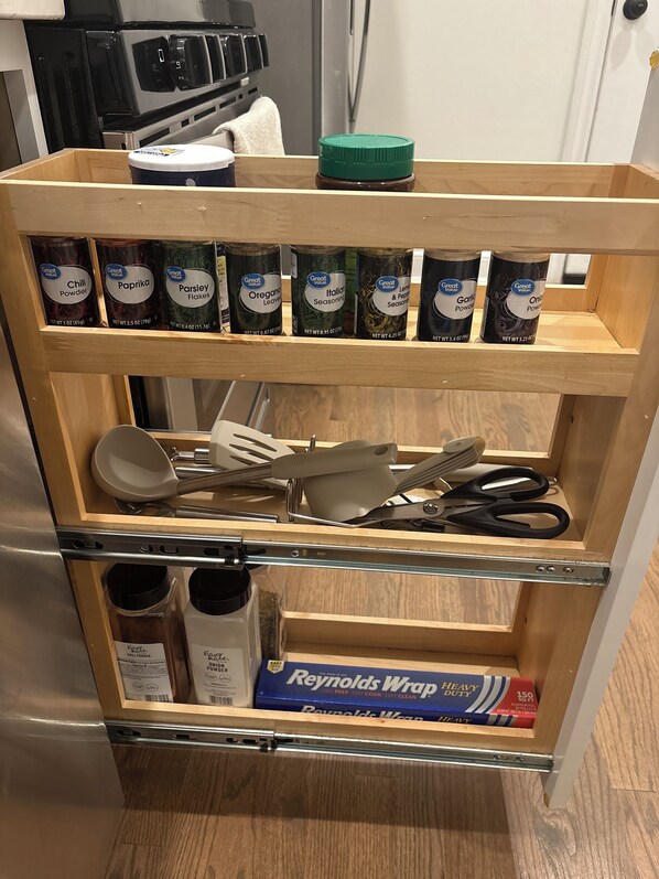 A kitchen shelf with various spices and cooking utensils.