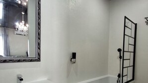 A modern bathroom with a large mirror, a sink, a vanity, a bathtub, and a shower. - La Discrète Romantique, apartment with jacuzzi (Charavines)