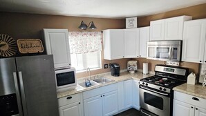 A modern kitchen with white cabinets, stainless steel appliances, a microwave, and a stove.