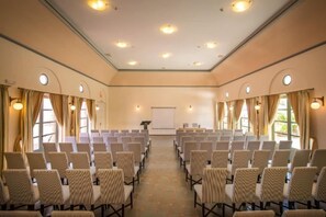 Ett konferensrum med rader av stolar, en projektorduk och en talarstol.