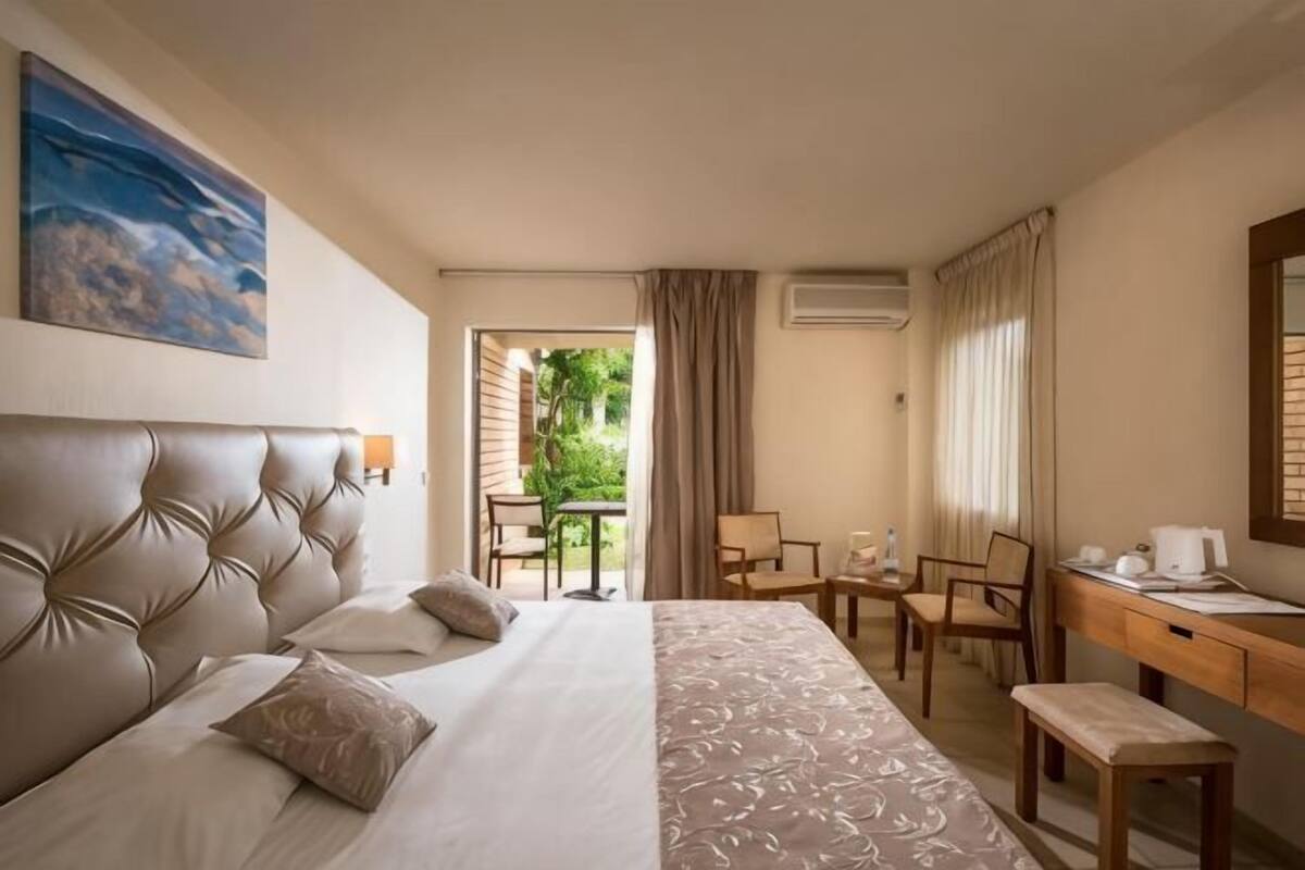 A hotel room with a large bed, a desk, a chair, and a small table.