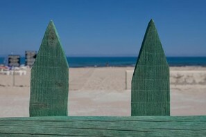 Two wooden posts on a beach with a clear sky and ocean in the background. - Bella Beach Hotel (Agkisaras)