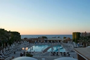 Un espace aménagé au bord de la piscine, avec des chaises longues et des parasols, offrant une vue sur la mer.