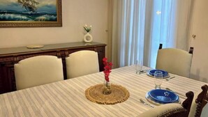 Un comedor con mantel a rayas, un florero con flores y un cuadro en la pared.
