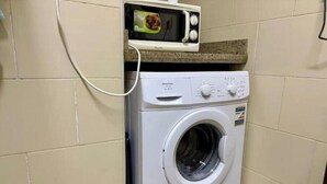 Una lavadora de carga frontal con un panel de control y un microondas encima.