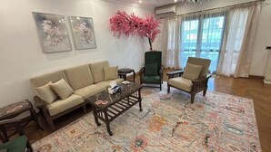 A living room with a sofa, two armchairs, a coffee table, a decorative plant, and a patterned rug. - Vintage Charm: 3BR, 2 baths in the heart of Zayed (Sheikh Zayed)