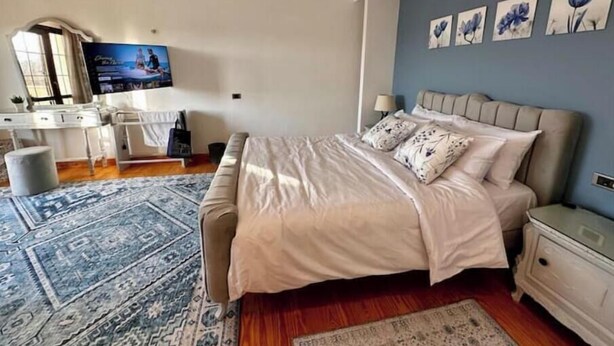 A bedroom with a bed, bedside tables, a desk, and a television. - Vintage Charm: 3BR, 2 baths in the heart of Zayed (Sheikh Zayed)
