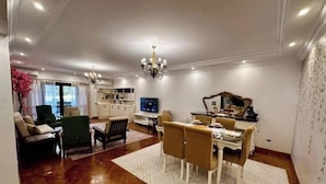 A spacious living room with a dining area, wooden flooring, and a chandelier. - Vintage Charm: 3BR, 2 baths in the heart of Zayed (Sheikh Zayed)