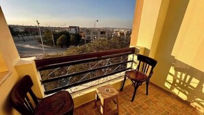 A balcony with two wicker chairs and a small table, overlooking a cityscape. - Vintage Charm: 3BR, 2 baths in the heart of Zayed (Sheikh Zayed)