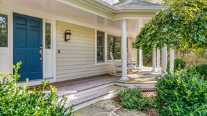 A house with a blue door, a porch with a rocking chair, and a covered area with columns.
