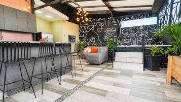 Una cocina moderna con barra, zona de estar con sofá y sillas, y una pared decorativa con diseños abstractos.