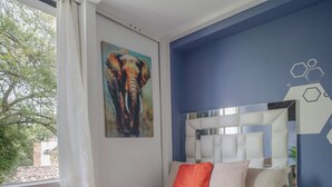 Une chambre à coucher avec un lit, un ventilateur de plafond, une table de chevet et une fenêtre avec des rideaux.