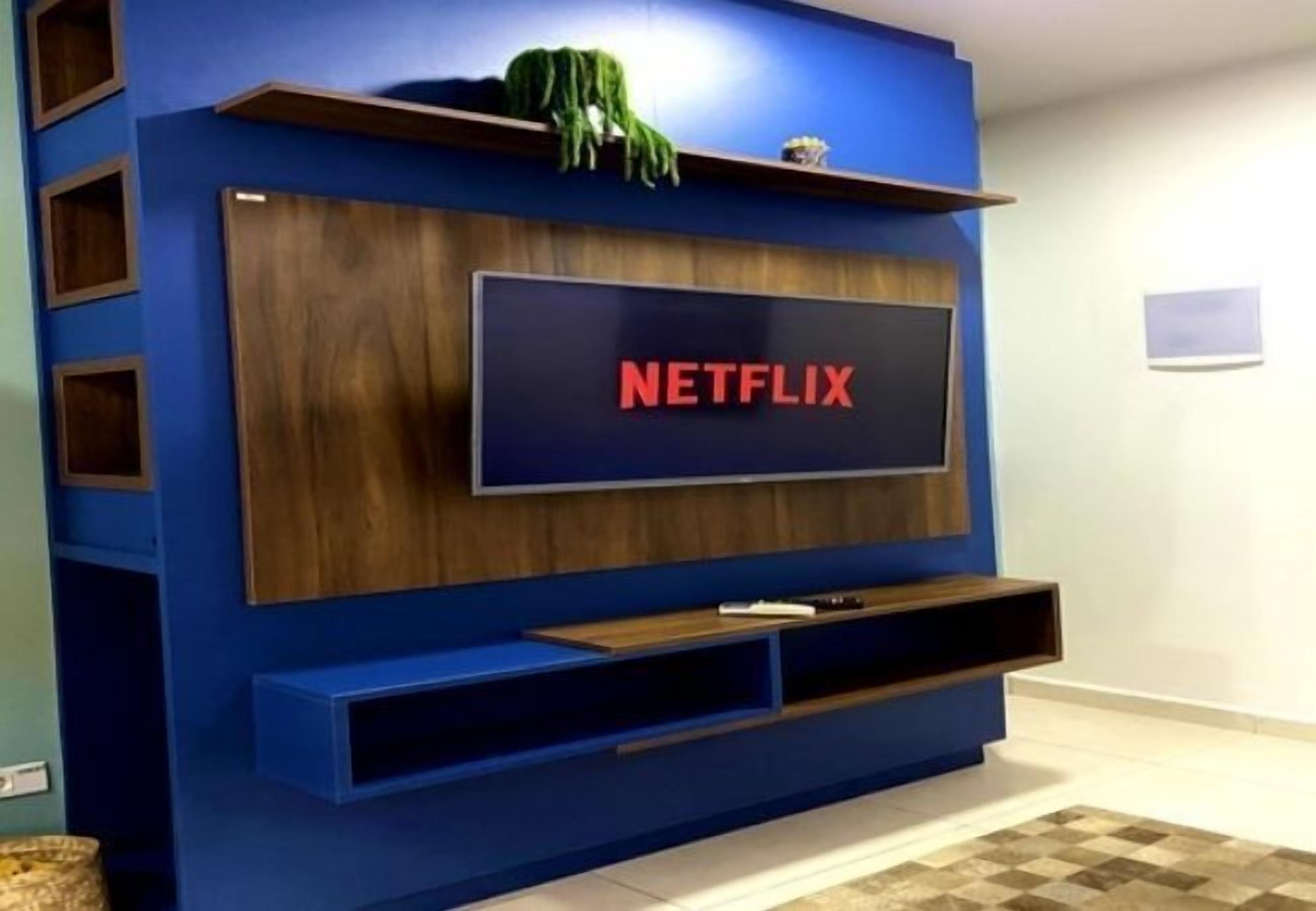 Un mueble moderno para entretenimiento con un televisor de pantalla plana grande que muestra el logotipo de Netflix.