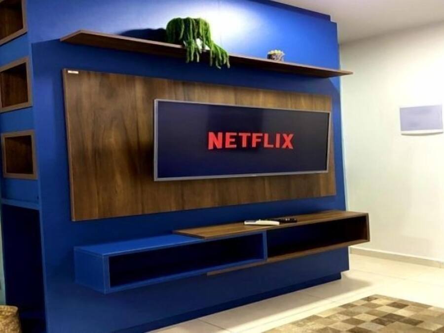 Un mueble moderno para entretenimiento con un televisor de pantalla plana grande que muestra el logotipo de Netflix.