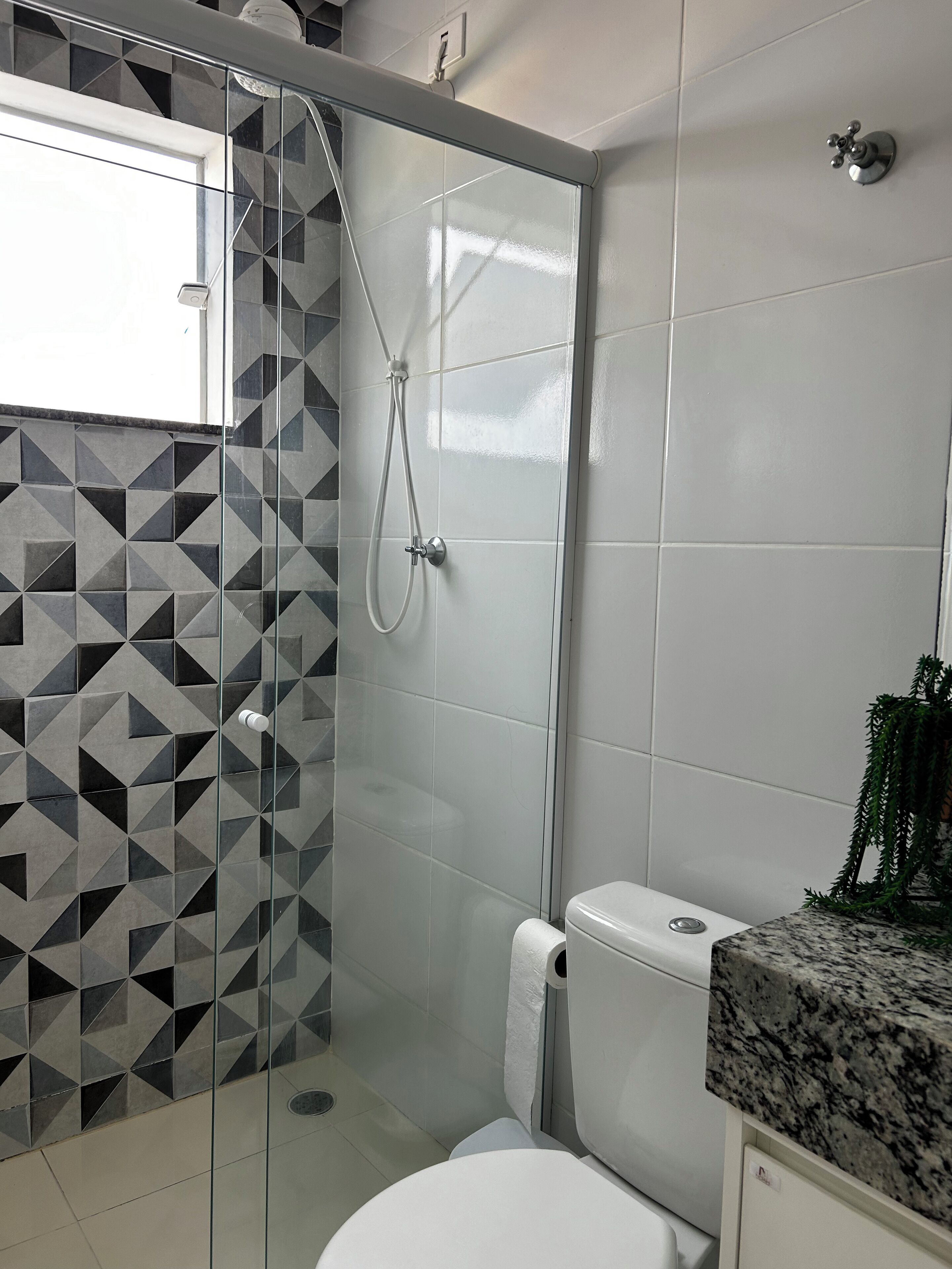 A bathroom with a glass-enclosed shower, a toilet, and a sink with a granite countertop.