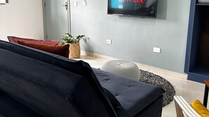 A modern living room with a large flat-screen TV mounted on the wall displaying 'NETFLIX'. - Mangata Loft (Itanhaém)