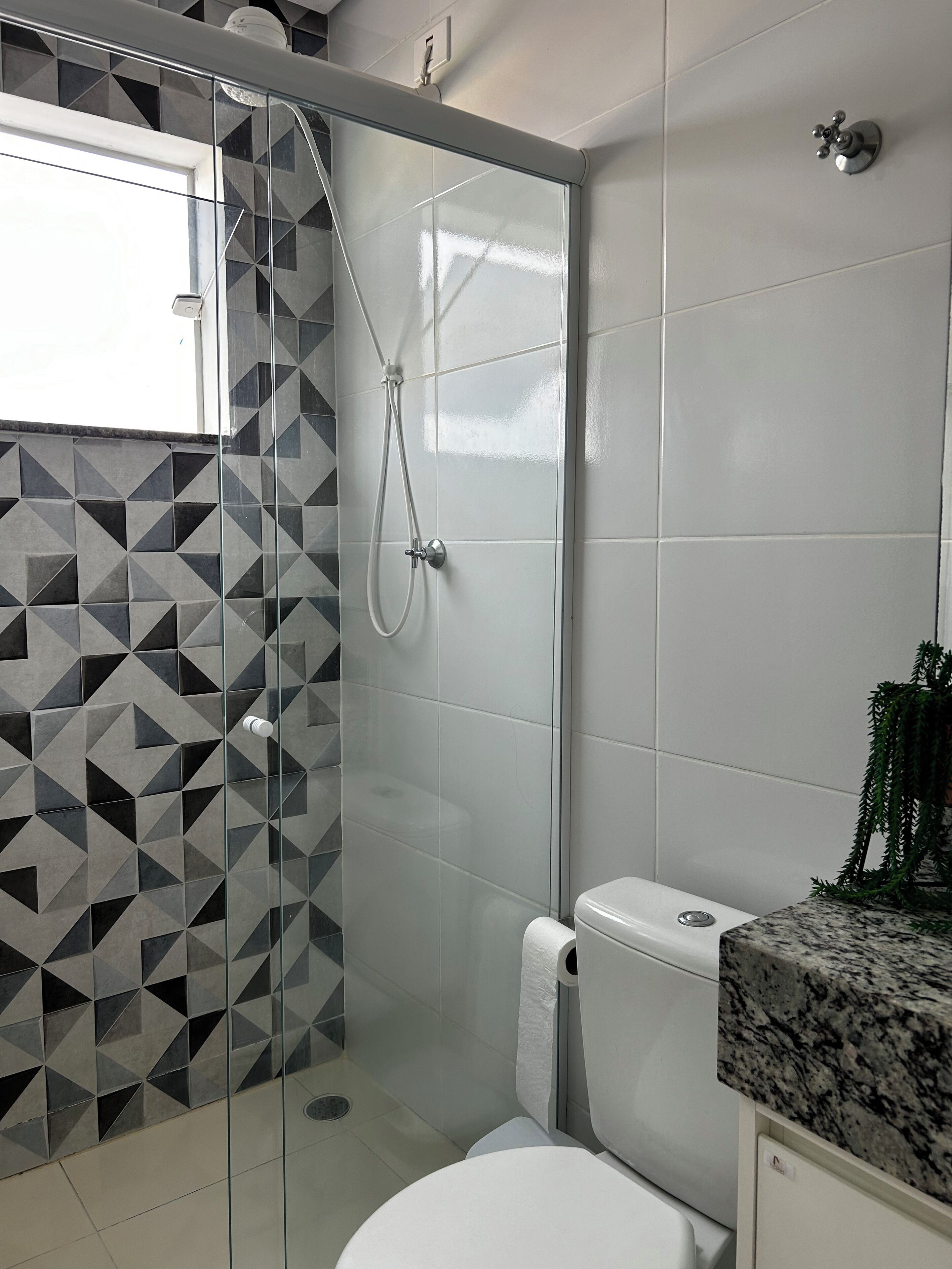 Un baño con ducha, inodoro y lavabo con encimera de granito.