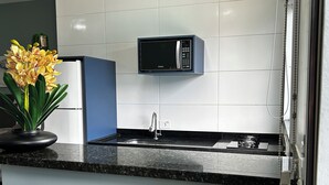 A modern kitchen with a built-in microwave, a sink, and a countertop. - Mangata Loft (Itanhaém)