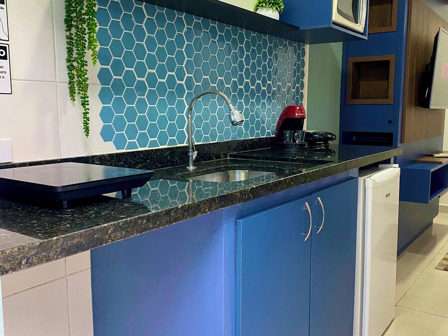 A modern kitchen with blue cabinets, a stainless steel sink, and a microwave.