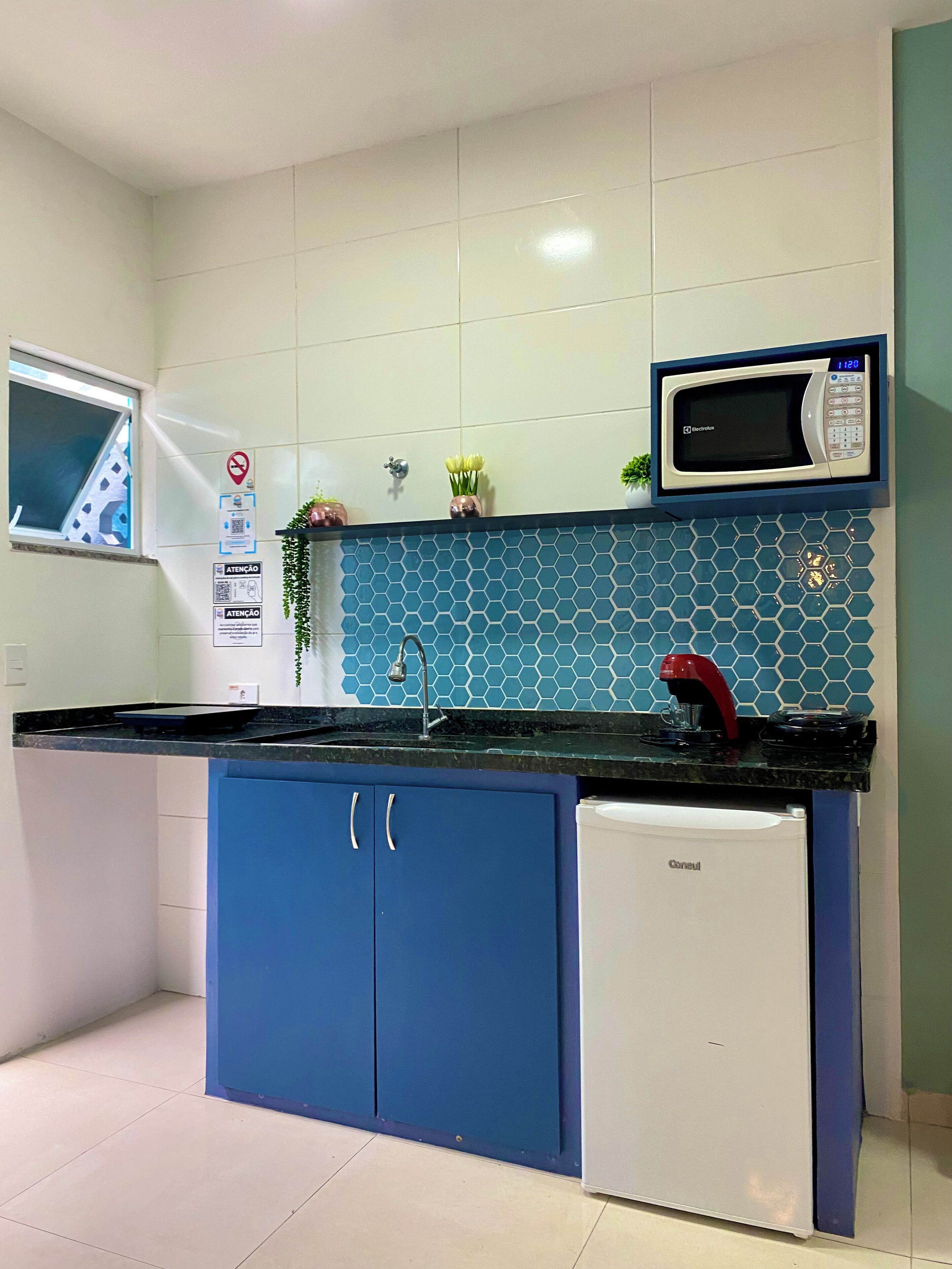 A compact kitchen with a microwave, sink, and a small refrigerator.