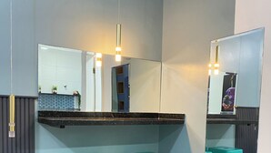 A bathroom with a mirror, two turquoise stools, a blue cabinet, and a tiled floor. - Mangata Loft (Itanhaém)