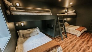 A bunk bed room with a ladder, a desk, and a window. - The Roosevelt | Modern Cabin in the Trees (Logan)